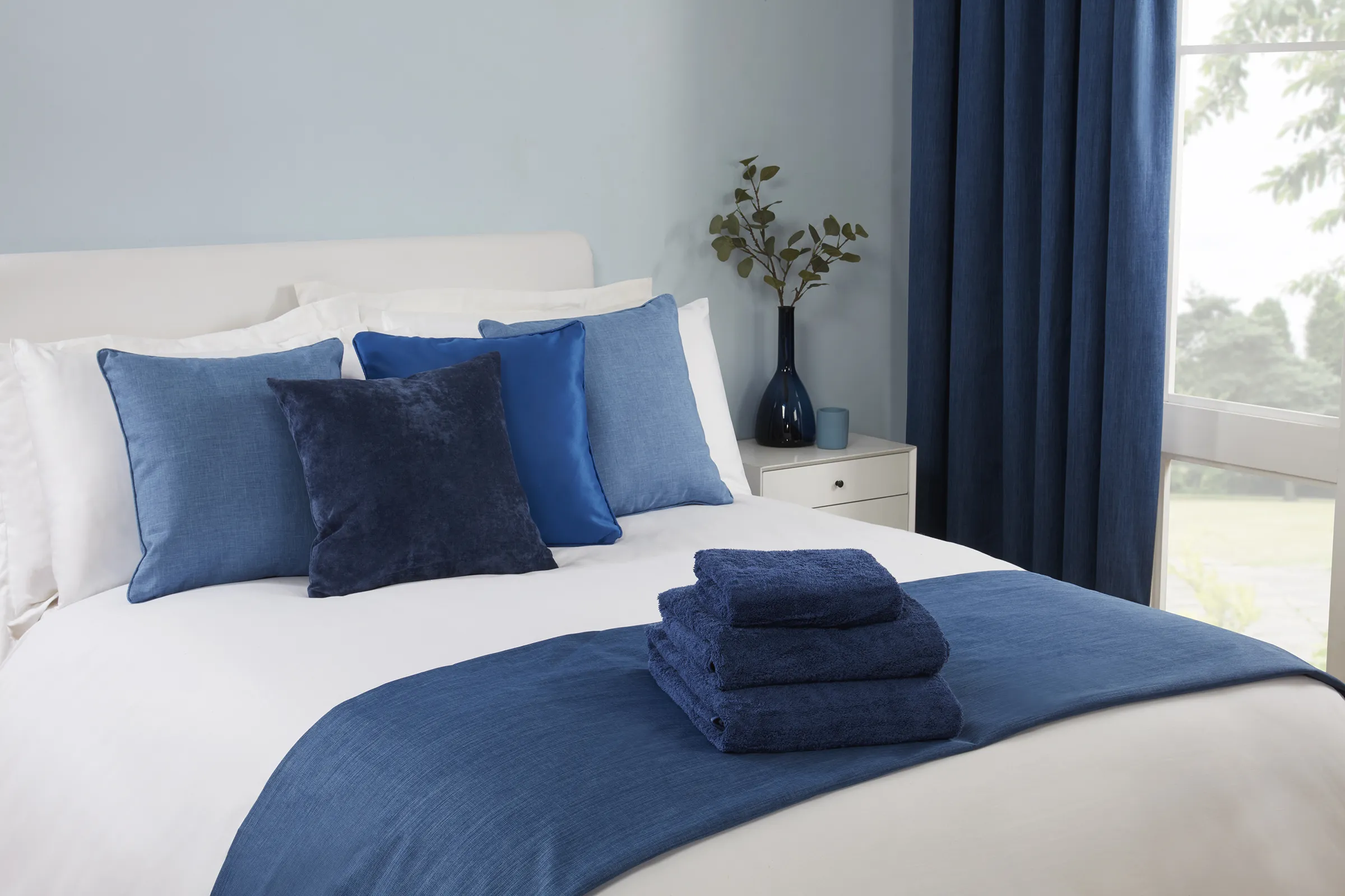 Blue cushions, towels and white bed linen for commercial accommodation